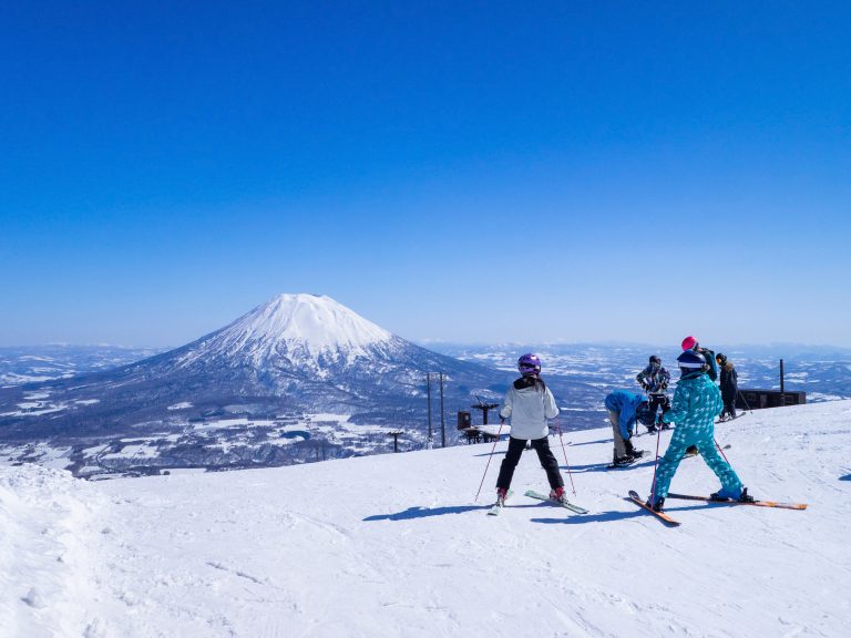 Skiers,looking,at,snowy,volcano,on,a,clear,day,in