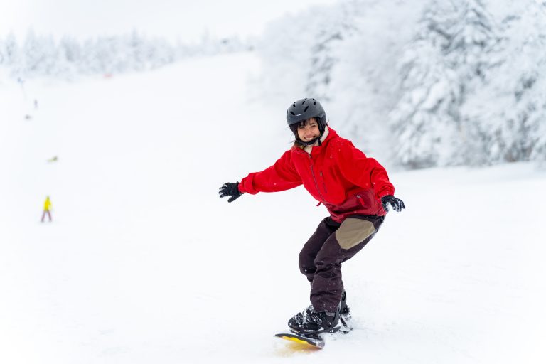 Young,asian,woman,practicing,snowboard,on,snowy,mountain,slope,at